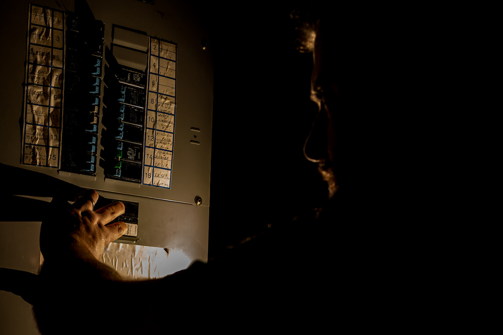 Knowledge Base Man Checks Home Fuse Box in a Dark Power Outage