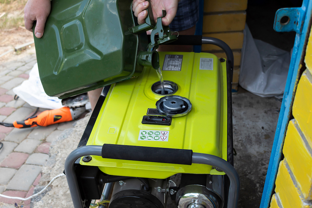Electric Generators: The Ultimate Guide A man pours gasoline into a generator on the doorstep.